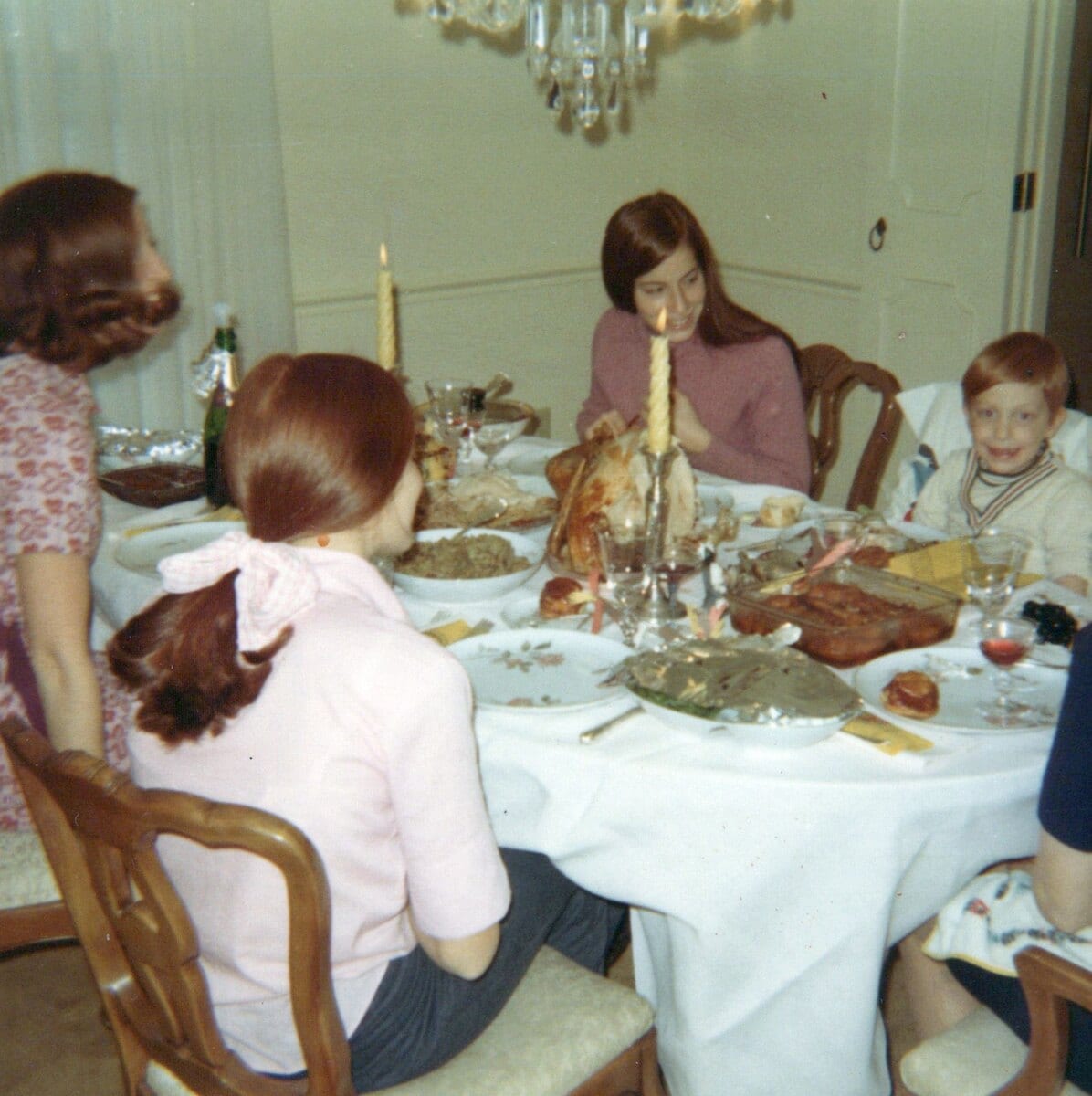 A 1970s dining room at a holiday meal, a turkey on the table and candles lit